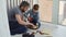 Little boy is focused on sawing piece of wood with hand saw with his father helping and teaching him. United family