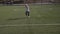 A little boy in a football uniform kicks a penalty on the football field.