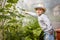 A little boy found the first young green cucumber in a greenhouse