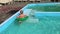 A little boy frolic in the pool on inflatable circles.