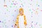Little boy in a fun bright giraffe costume on a white isolated background with confetti, children`s birthday, place for text