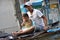 A little boy is gesturing a wai to the photographer as he passes with his father on a bamboo raft in a flooded street of Bangkok,