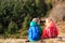 Little boy and girl with backpacks having rest in mountains