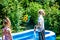 Little boy and girl filling swimming pool with water