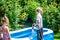 Little boy and girl filling swimming pool with water