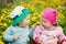 Little boy and girl in hats sitting on the field with soft toys in summer