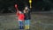 A little boy and girl in rubber boots are walking through the forest and holding shovels.