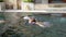 Little boy and girl swim underwater in swimming pool