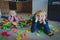 Little boy and girl tired stressed exhausted with toys scattered indoors