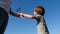 A little boy gives a bouquet of wild flowers to his mother. Bottom view against the blue sky. Emotions of happiness