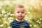 Little boy in the glade of chamomiles in summer