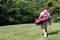 Little boy golfer walking with his golf bag on the fairway