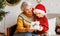 Little boy grandson giving Christmas gift box to smiling grandmother during winter holidays