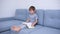 Little boy in gray clothes sitting on a gray sofa and learning to read a yellow book. Love for reading, family time. Self-