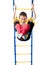 Little boy hanging on sports rings and keeps kicking a red heart