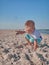 Little boy having on beach fun with the sand. Baby playing on the seaside in summertimes. Summer rest concept. Happy