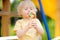 Little boy having fun and eating big lollipop on outdoor playground