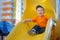 Little boy having fun on a playground outdoors in summer. Playful toddler on a slide.