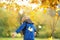 Little boy having fun during stroll in the forest at sunny autumn day. Child playing maple leaves. Baby tossing the leaves up.