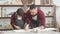 Little boy helps his carpenter father measuring the wooden plank in workshop.