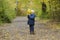 Little boy hiding behind an armful of yellow leaves. Autumn fore