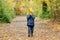 Little boy hiding behind an armful of yellow leaves. Autumn forest.