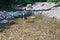 Little boy hiker crosses mountain creek ford