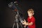 A little boy himself adjusts a large telescope.