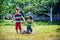 Little boy and his brother play in summer park. Children with colorful clothes jump in puddle and mud in the garden.