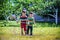 Little boy and his brother play in summer park. Children with colorful clothes jump in puddle and mud in the garden.