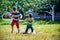 Little boy and his brother play in summer park. Children with colorful clothes jump in puddle and mud in the garden