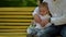 Little boy and his dad does not want to try on a bow tie. They are sitting on a park bench.