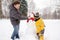 Little boy with his father building snowman in snowy park. Active outdoors leisure with children in winter