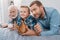 Little boy, his father and grandfather lying on the bed with baseball ball and mitt and watching a