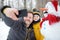 Little boy and his father taking selfie on background of snowman in snowy park. Active outdoors leisure with children in winter