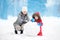 Little boy with his mother/babysitter/grandmother building snowman in snowy park