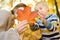 Little boy and his mother having fun during stroll in the forest at sunny autumn day. Child and mom playing maple leaves. Family