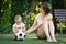 Little boy and his mother playing with soccer ball at training ground. Mom and son play together at football field outdoors