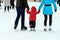 A little boy with his parents skates on the rink in the winter. Active family sport, winter holidays, clubs.