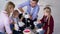 little boy and his sister have fun with mom and dad mixing red pigment with paint in bucket while renovating and