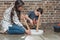 Little boy and his young mother sitting on floor at home assembling a coffee table