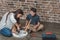 Little boy and his young mother sitting on floor at home assembling a coffee table