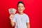 Little boy hispanic kid holding 10 colombian pesos banknotes looking positive and happy standing and smiling with a confident