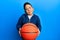 Little boy hispanic kid holding basketball ball clueless and confused expression