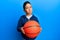 Little boy hispanic kid holding basketball ball skeptic and nervous, frowning upset because of problem