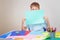 Little boy holding blank empty colored paper sheet covered face.