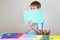 Little boy holding blank empty colored paper sheet covered face.