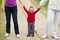 Little boy holding hands of his parents