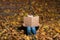 Little boy holding large book in hands and sitting on fallen autumn leaves. Child loves to read