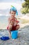 Little boy holding red five point starfish and bucket in his han